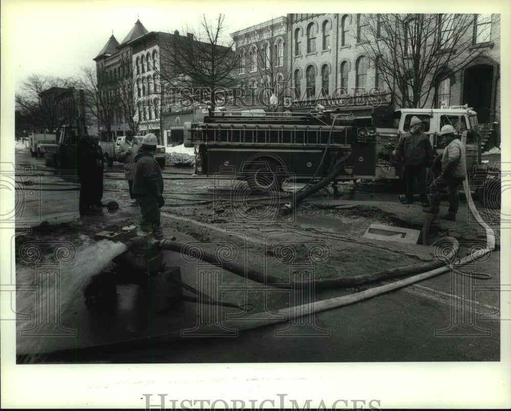1990 Saratoga, NY fire crew pumps water from leak under Broadway St - Historic Images