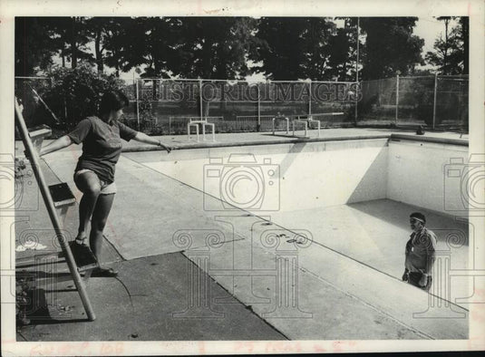 1980 Schenectady, NY parks crew drains park pool to remove glass - Historic Images