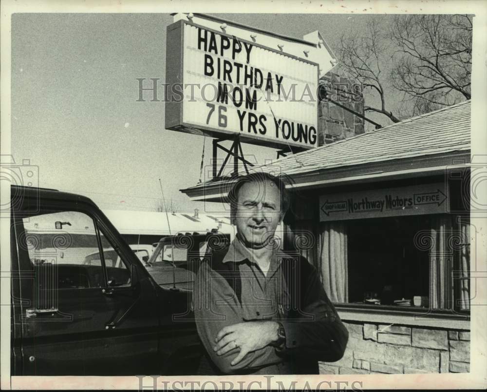 1980 Vic Schneider of Norway Motors with sign for mothers birthday, - Historic Images