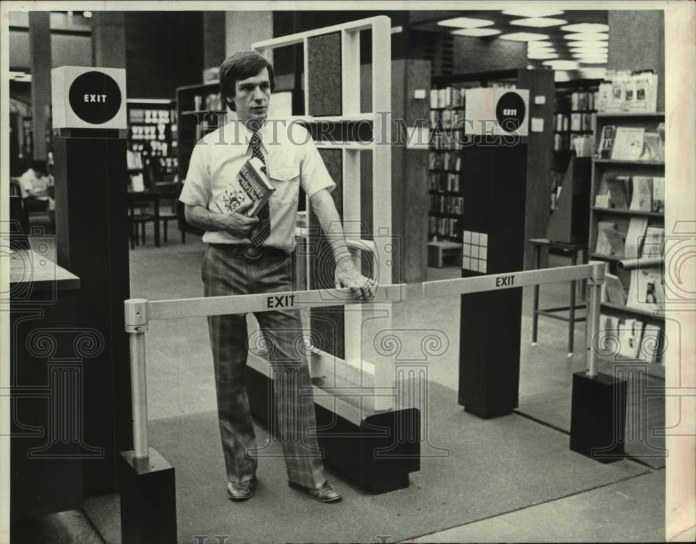 1979 Schenectady, NY County Librarian demonstrates anti-theft device - Historic Images