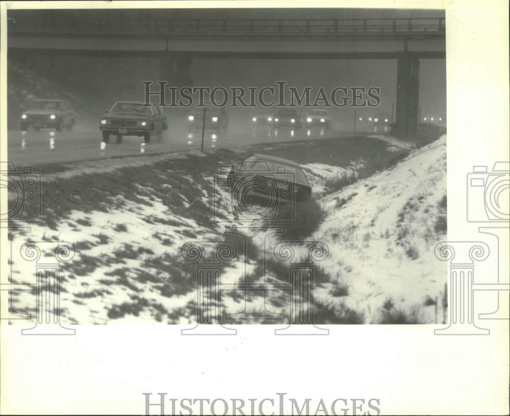 1991 Press Photo Traffic passes car in ditch along I-87 in Albany, New York - Historic Images