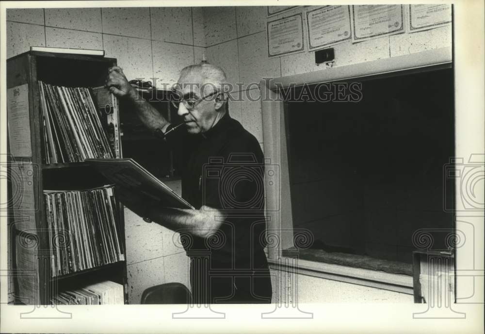 1977 Reverend Angelus Netzer looking at record albums - Historic Images