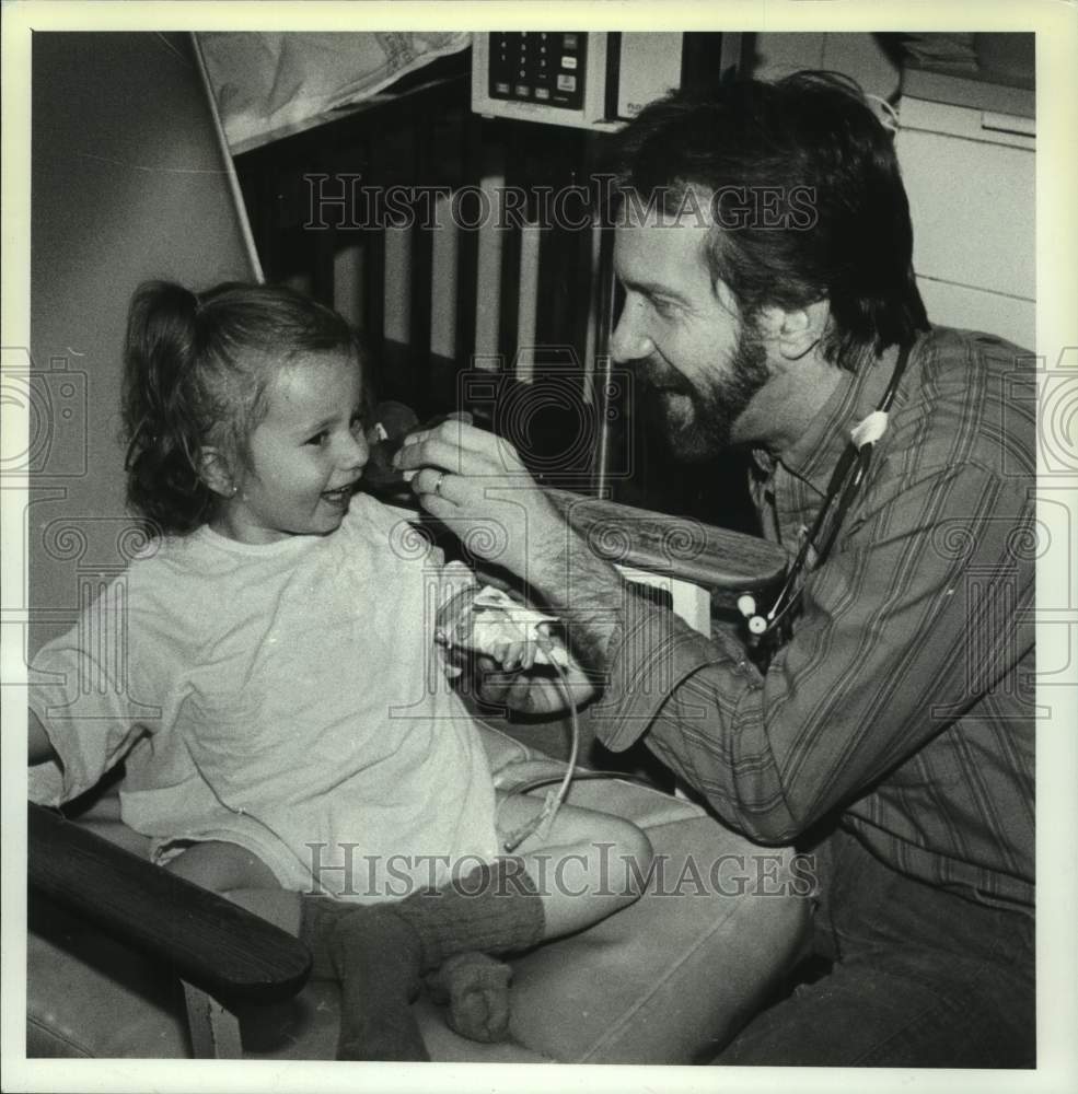 1990 Press Photo Steve Jones, Pediatric nurse, is shown examining a young girl - Historic Images