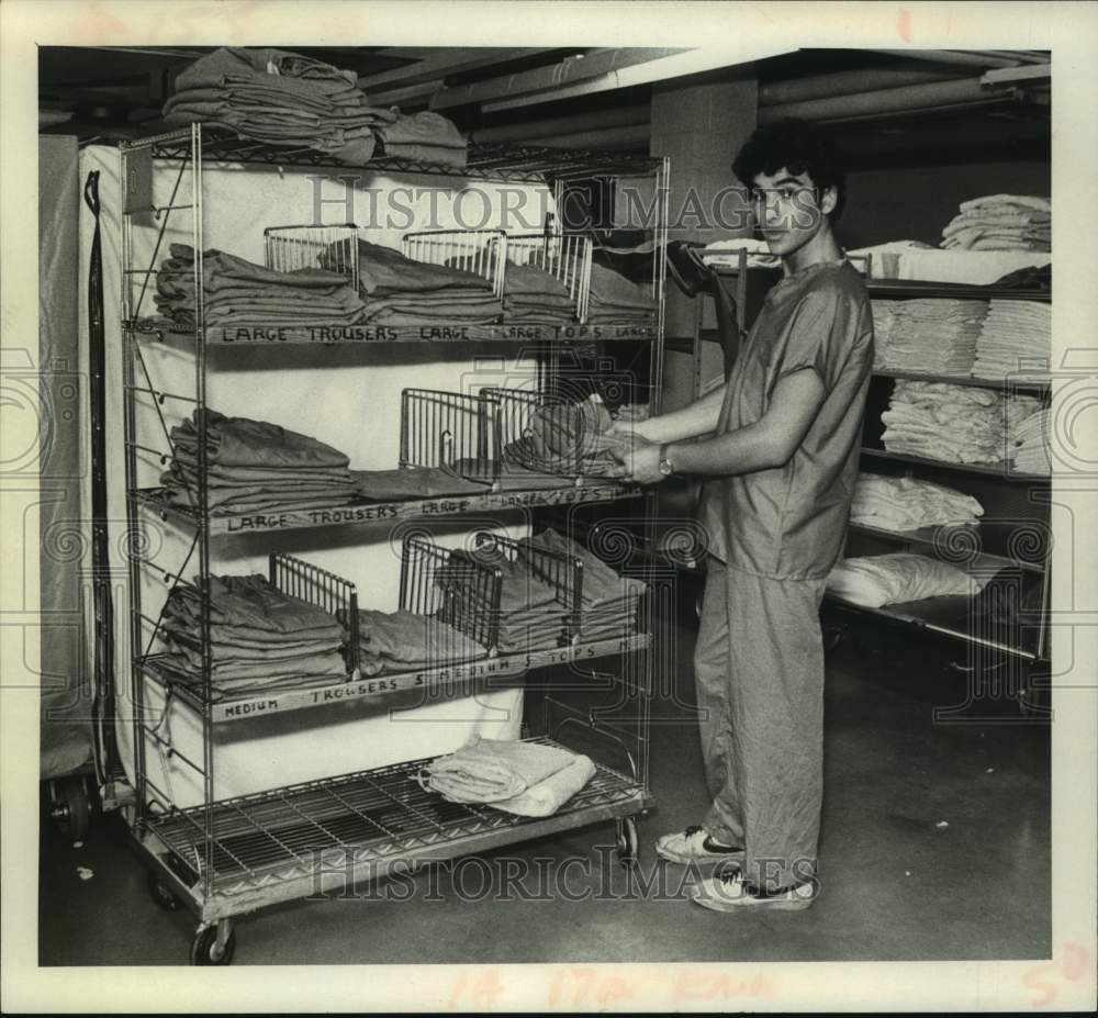 1981 Raul Tabor arranges scrub suits on cart at St Peters Hospital - Historic Images