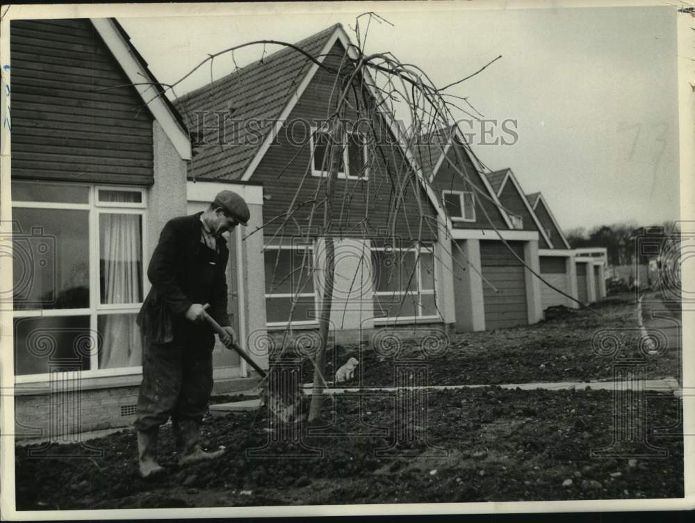 Press Photo Man planting a tree outside new homes in Cumbernauld, Scotland - Historic Images