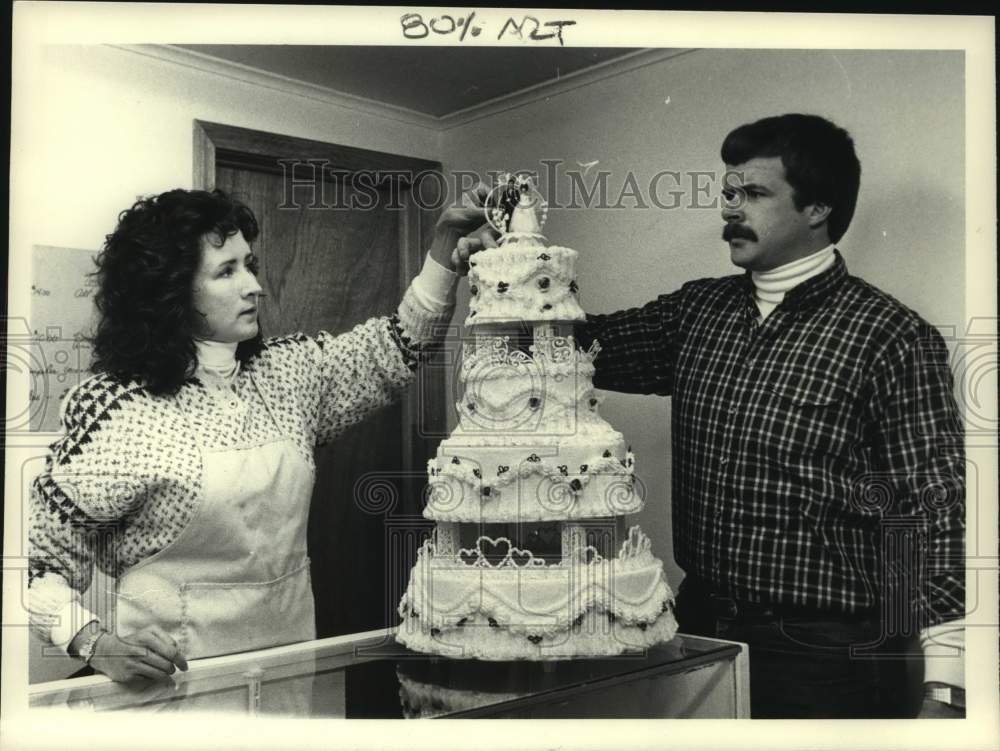 1985 J and S Watkins, couple finishing wedding cake decorations - Historic Images