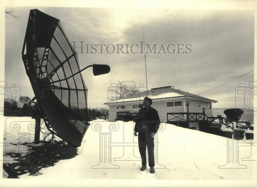 1986 Press Photo Carl Warner inspects satellite dish outside his New York home - Historic Images
