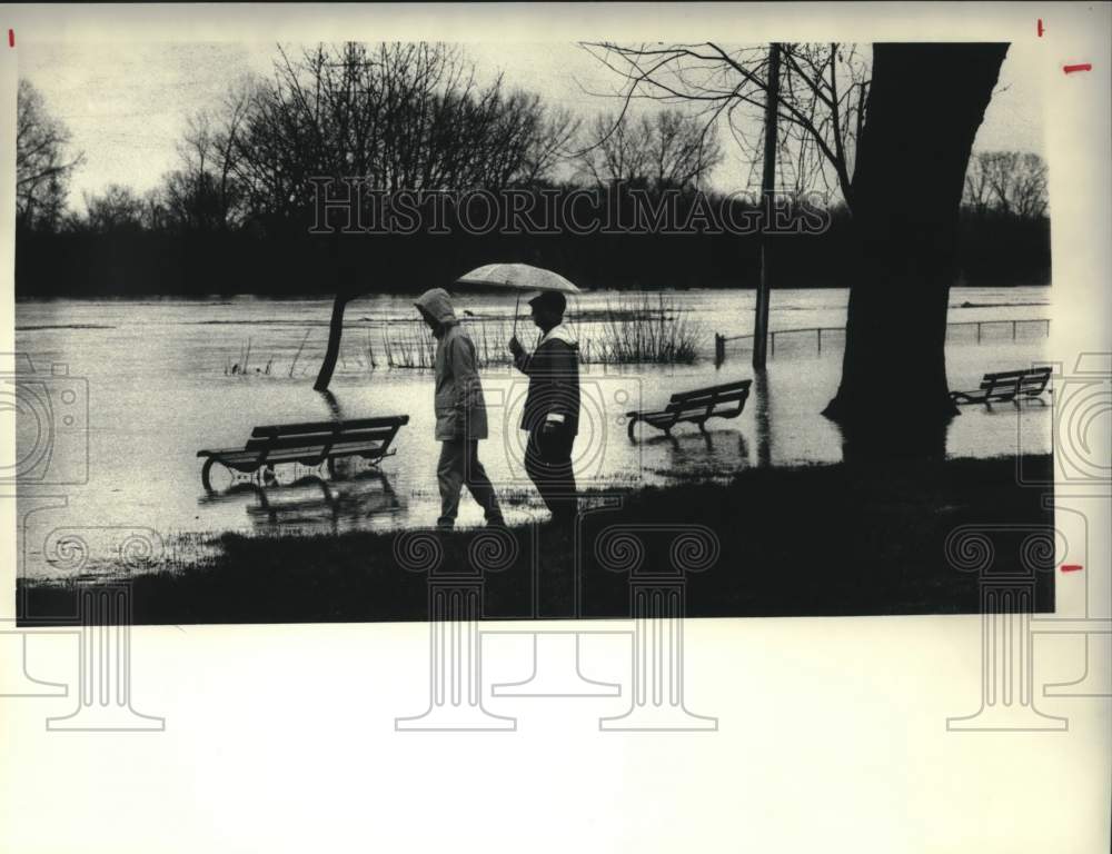1987 Press Photo Couple strolls through flooded park in Schenectady, New York - Historic Images