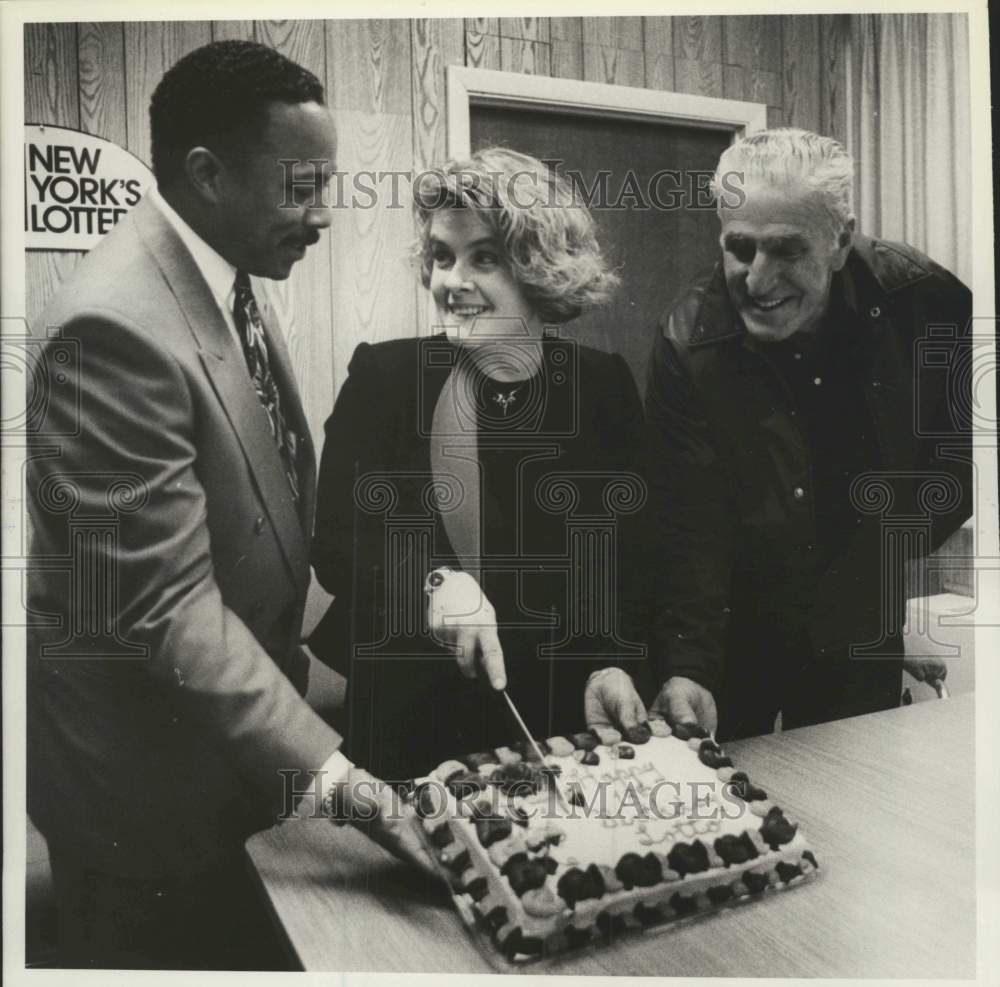 1992 Lottery official cuts cake for winning players in Albany, NY - Historic Images