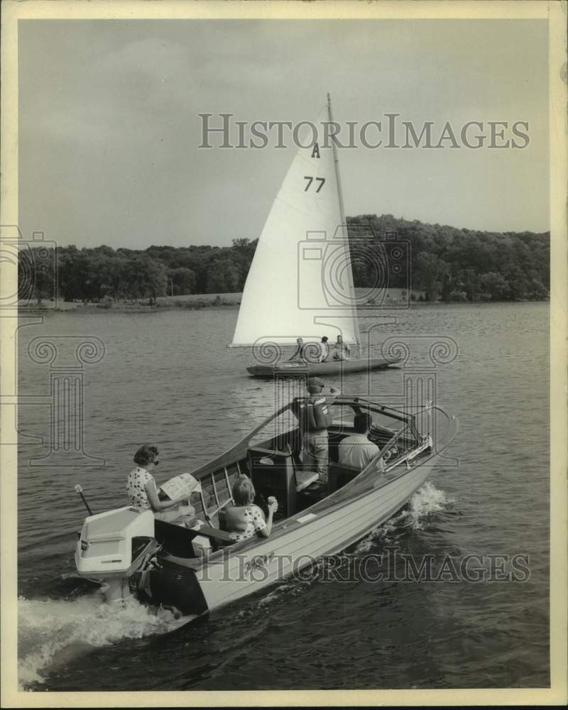 Press Photo Family on small motor boat rides past family on a sailboat - Historic Images