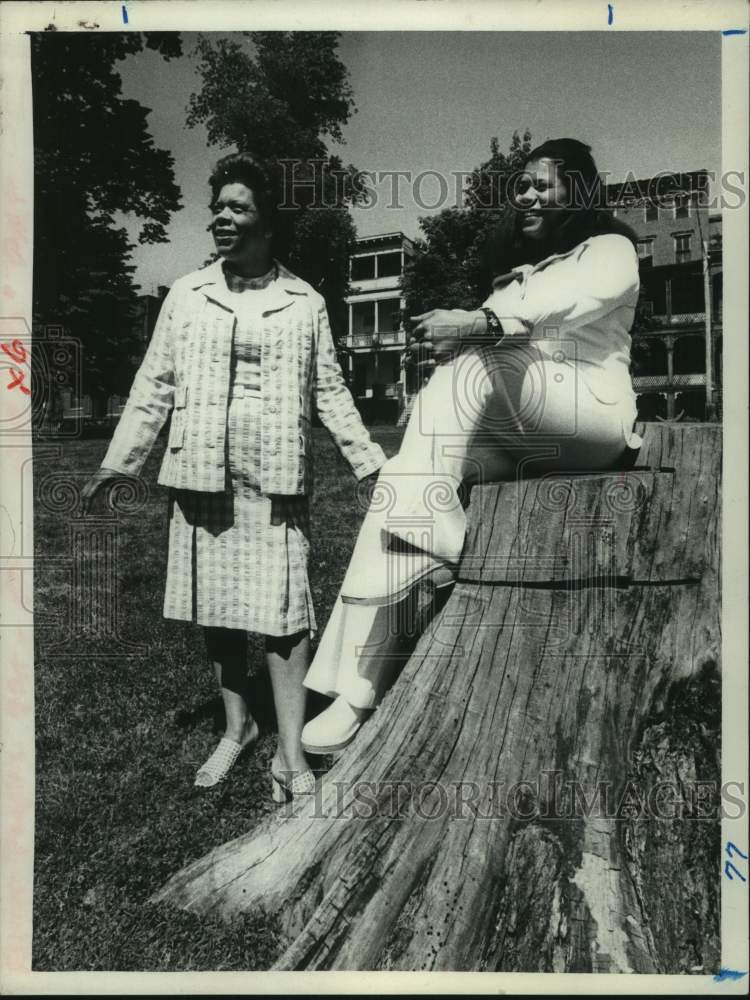 1975 Press Photo Sara Logan talks to Miriam Ballow, who is sitting on tree stump - Historic Images