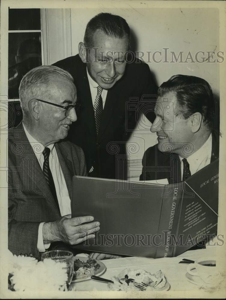 1961 Frank C Moore, Malcolm Wilson, & Governor Rockefeller read book - Historic Images