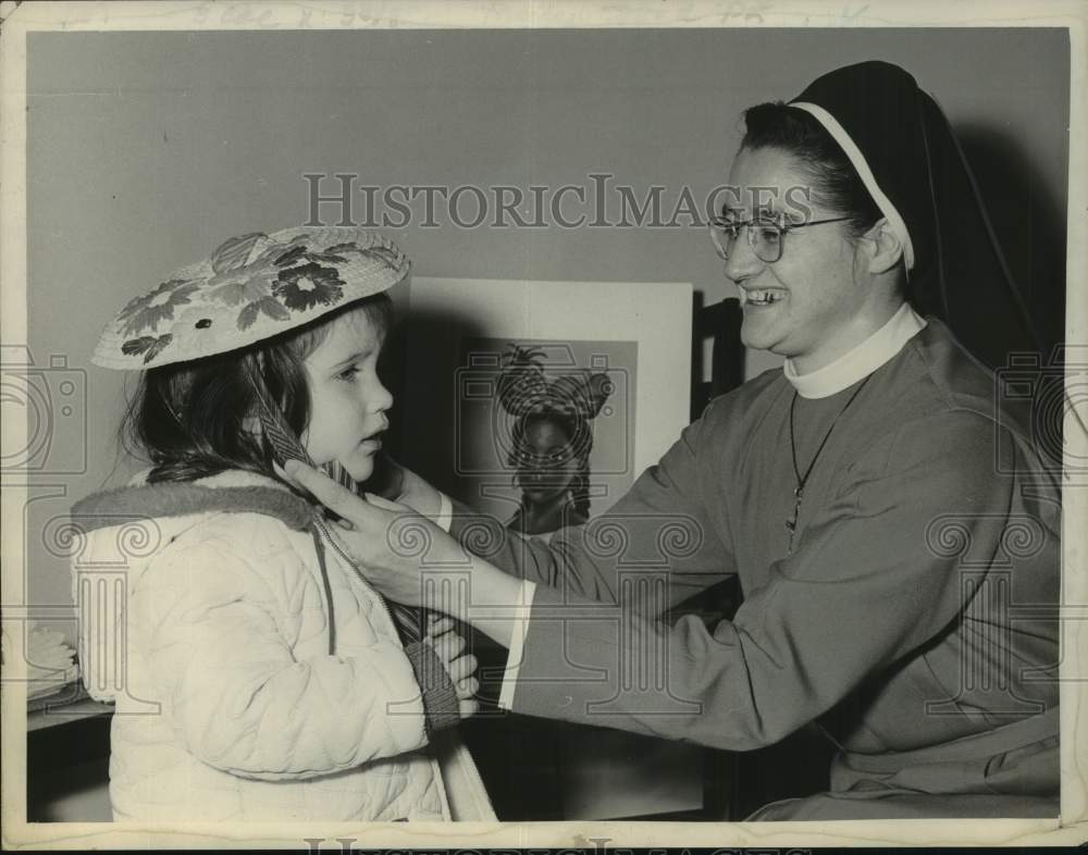 1964 Press Photo Sister Mary Baldwin adjusts child&#39;s hat in Albany, New York - Historic Images