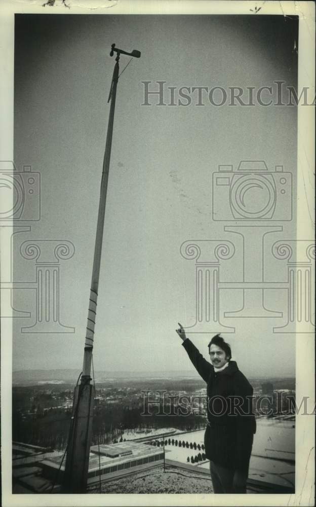 1977 Press Photo Bruce Bailey with weather gear on roof in Albany, New York - Historic Images