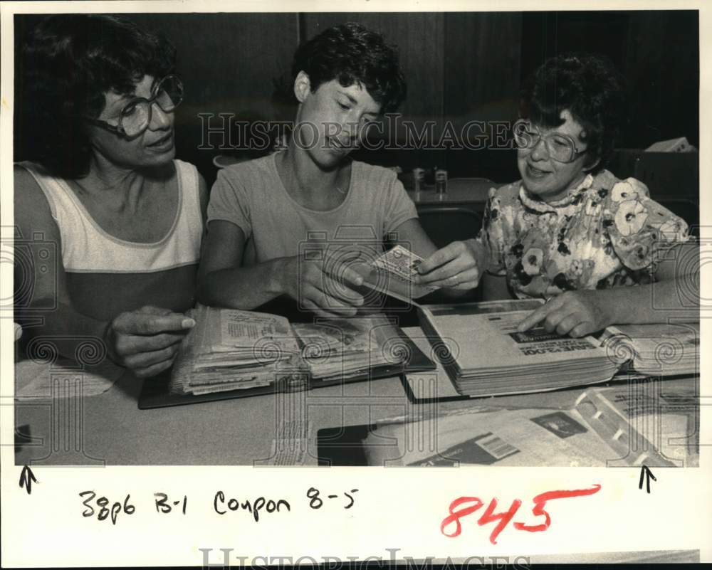 1984 Press Photo Group looks over coupons from binder in New York - tua73651- Historic Images
