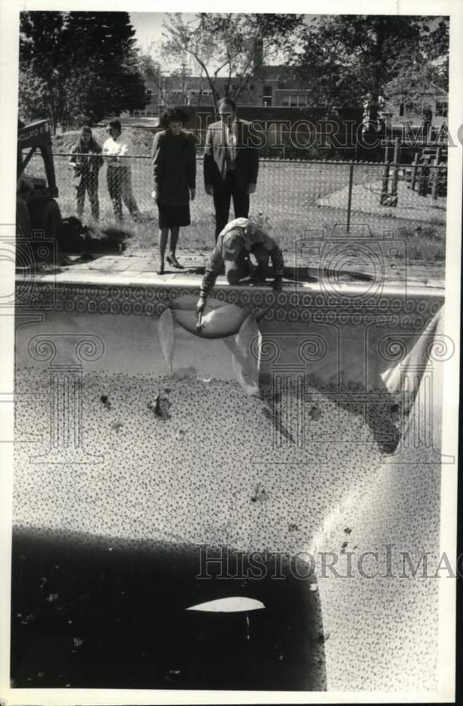 1990 Press Photo Group inspects damaged liner of swimming pool in New York - Historic Images