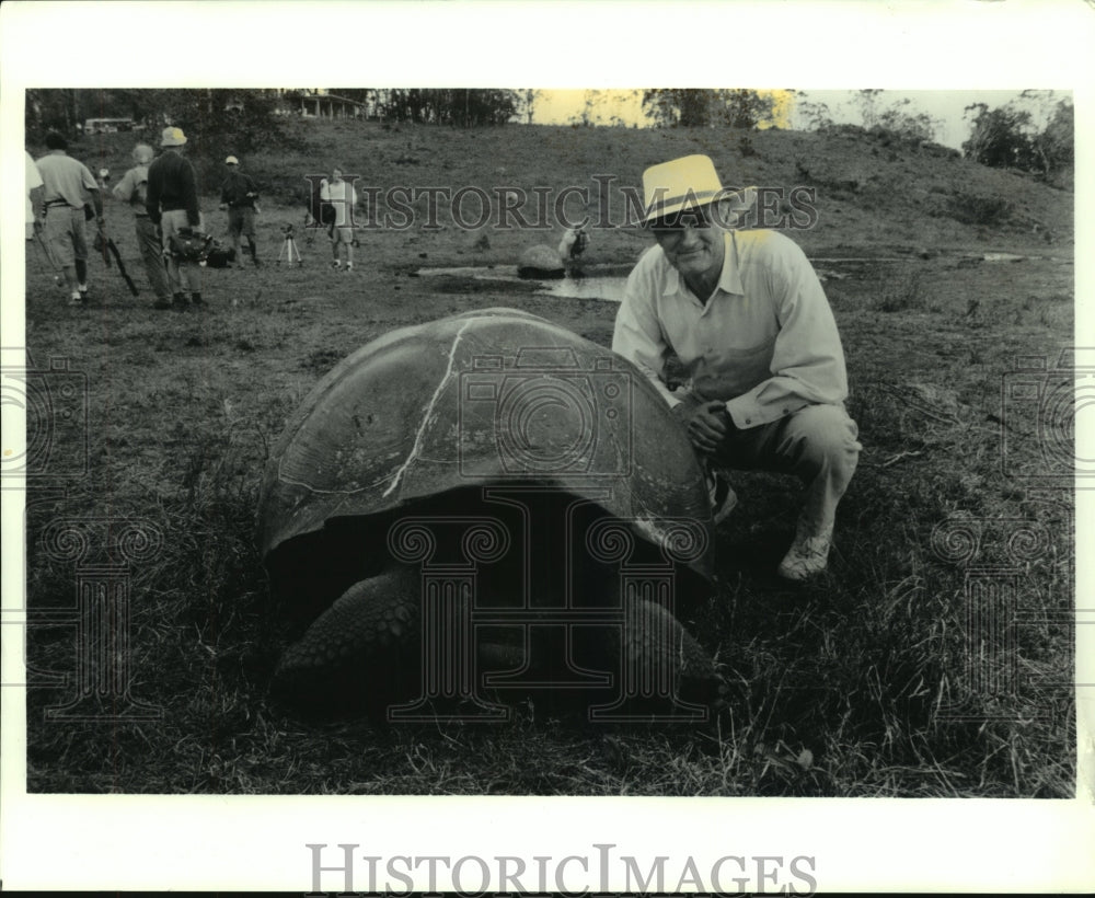 1999 Press Photo Alan Alda poses with giant tortoise on Galapagos Islands - Historic Images