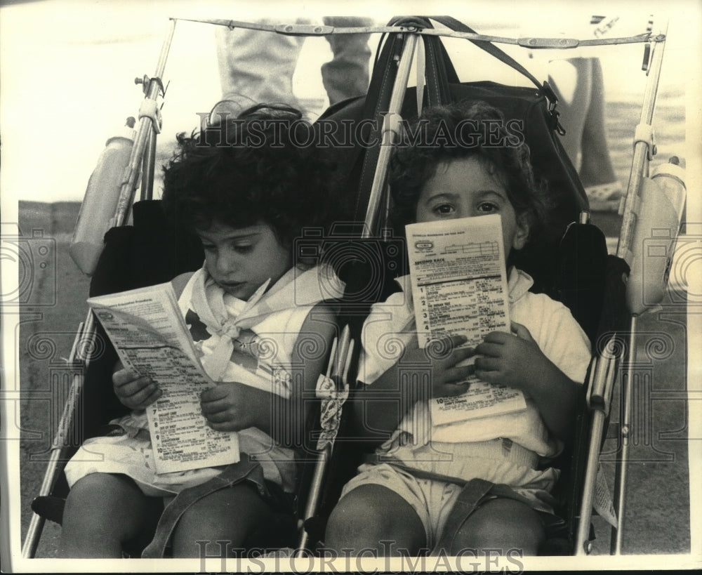 1980 Press Photo Two youngsters in stroller look over racing program at Saratoga- Historic Images