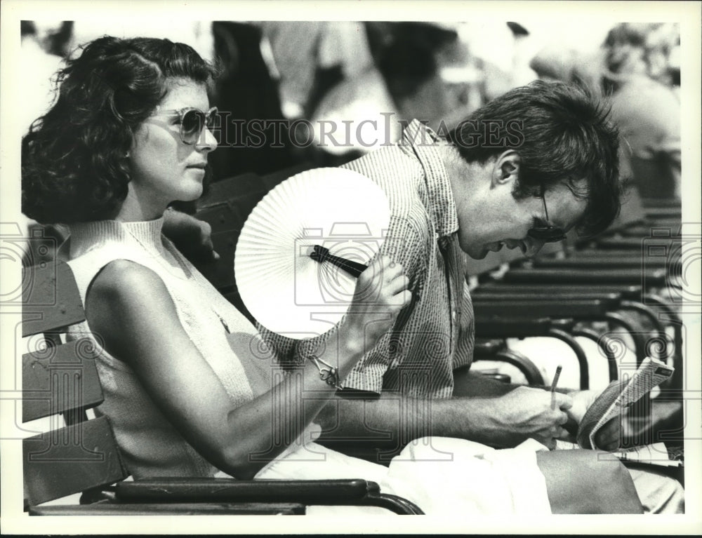 1988 Press Photo Patricia Haynes fans herself as husband Michael reviews program - Historic Images