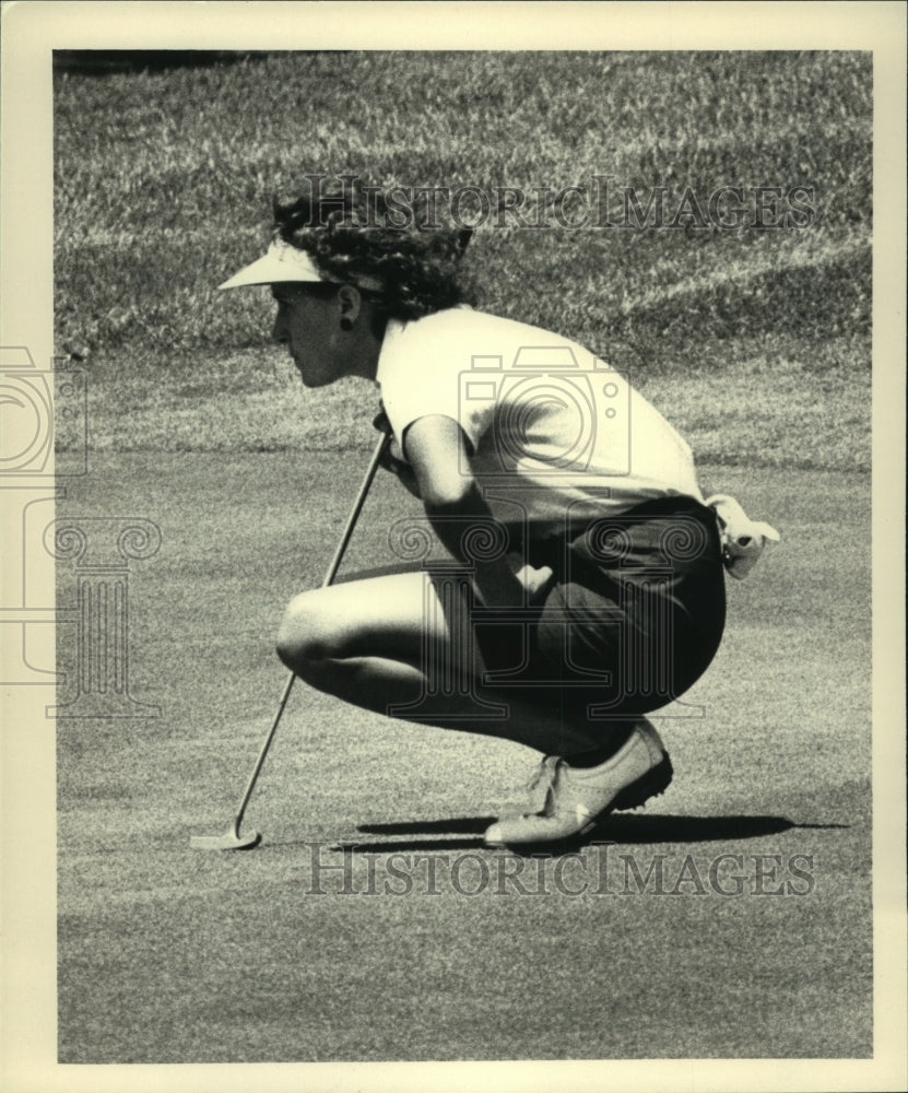 Golfer Tammie Green squats down to line up her putt during match - Historic Images