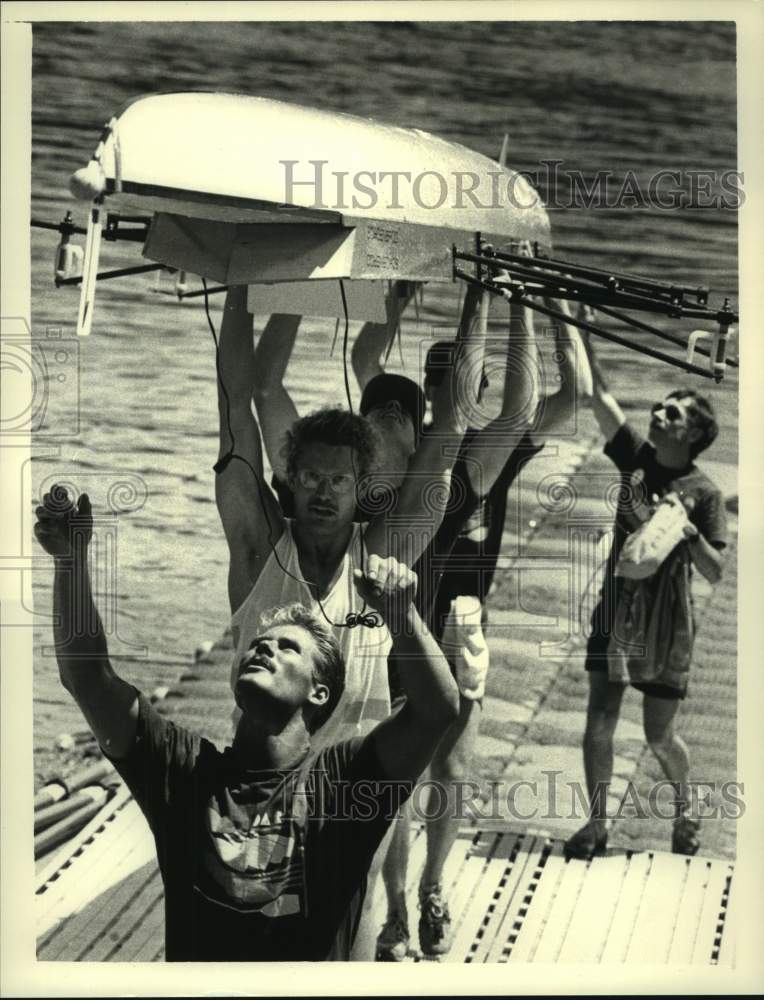 The four-man boat team from OARS carries their boat above their head - Historic Images
