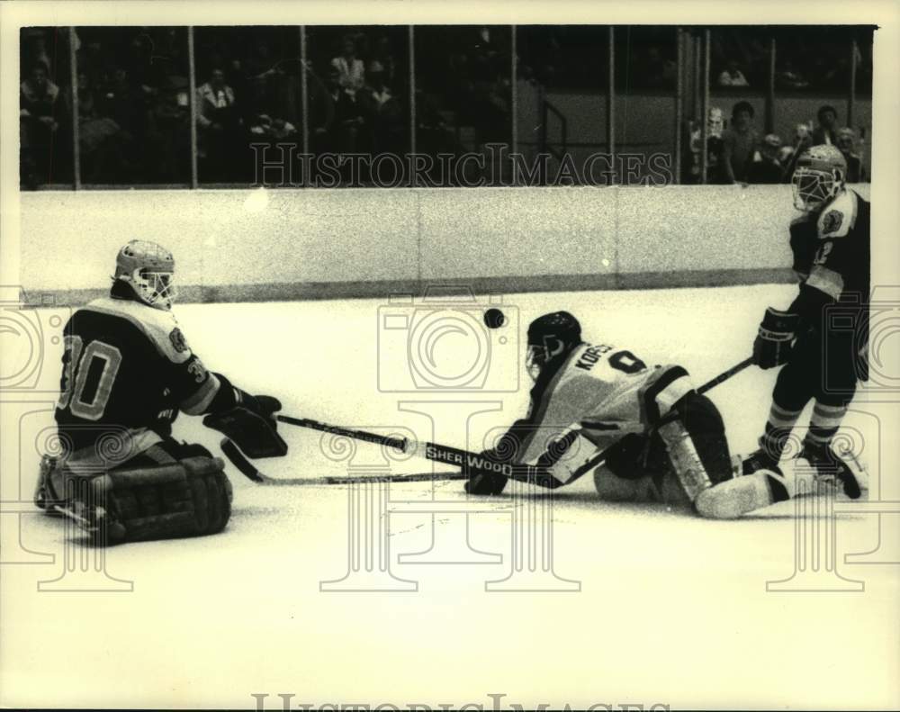 1986 Press Photo Clarkson hockey goalie #30 watches puck fly above RPI&#39;s #9 head - Historic Images