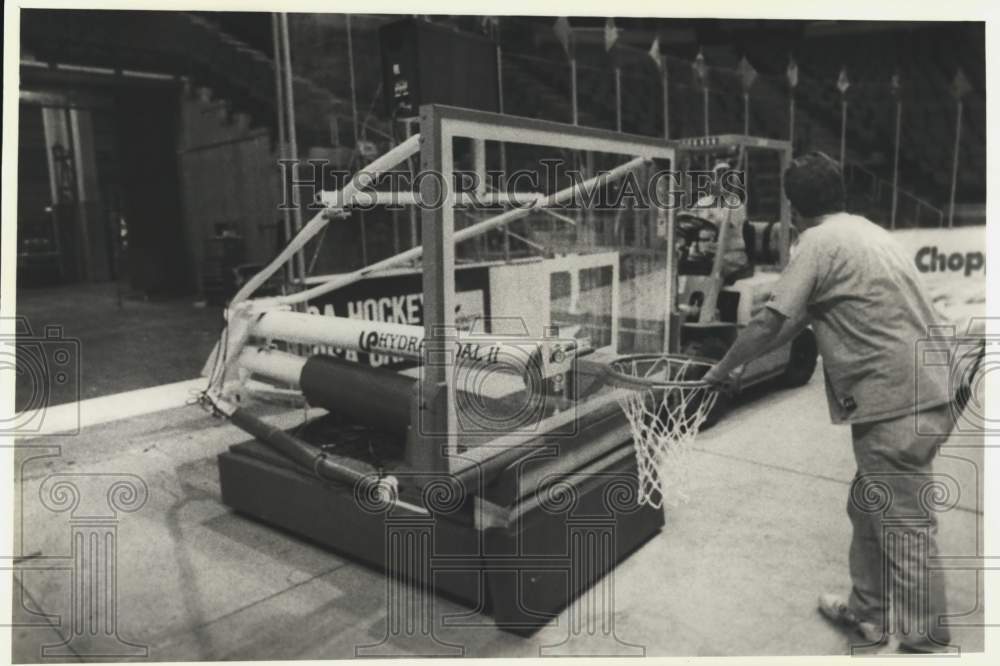 Press Photo An arena changeover worker pushes a basketball goal - tus06399 - Historic Images